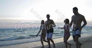 在日落时分在沙滩上散步的人群，夏季度假期间的两对混合种族夫妇交流