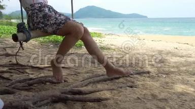 泰国普吉岛夏季的一天，一位女士在带着蓝天背景的热带海滩上荡秋千，放松<strong>身心</strong>，尽情享受