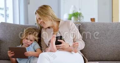母亲和女儿在客厅4k使用<strong>手机</strong>和<strong>数码</strong>平板电脑