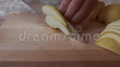 女人用刀把苹果切成薄片，放在厨房的桌子上的切割板上。