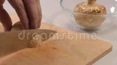 雄手用刀在<strong>切割</strong>板上切生蘑菇，然后把它们折叠成<strong>玻璃</strong>碗