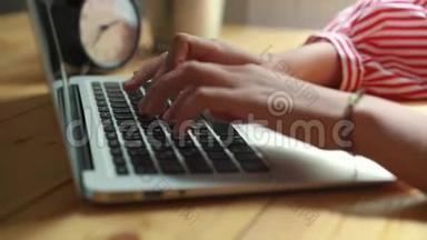 女人坐在笔记本电脑前的桌子旁，女人的手放在键盘上