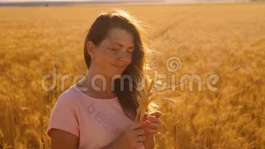 一个女孩在田野的肖像与小麦在日落剪影自然慢动作视频。 美丽的女孩在白田
