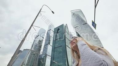 在市中心摩天大楼和<strong>高楼大厦</strong>的背景下，一个金发女孩正在打电话。