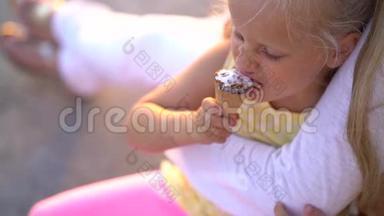 可爱的小女孩在<strong>妈妈怀里</strong>坐在长廊上吃冰淇淋