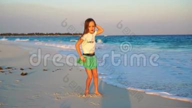 可爱的快乐小女孩在白色海滩日落。 可爱的孩子在热带海滨慢动作视频舞蹈