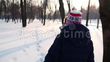 女孩穿过冬天公园的摄像机跟着她。