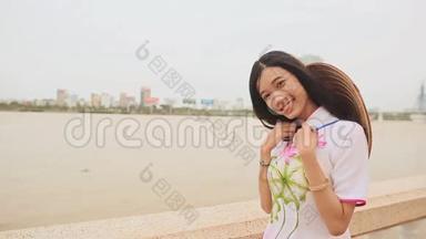 越南女孩穿着民族服装和服装在岘港市的海滨摆姿势。 在后面