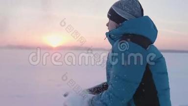 一个孩子在冬天户外玩耍，跑步，把雪扔到顶部。 美丽的日落。 户外运动