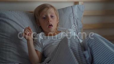 在床上生病的小男孩。 一个男孩在床上咳嗽时的超慢镜头。 婴儿流感概念