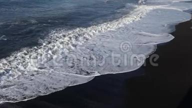 波浪<strong>跑到</strong>海滩上。 白色泡沫从黑色海滩的背景上的波浪。 海洋冲浪