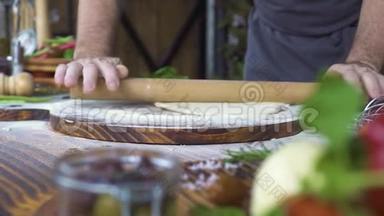 用擀面杖在桌上擀面皮. 厨师用木辊擀面饼