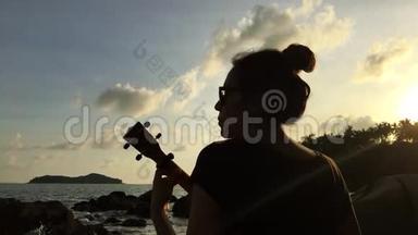 年轻的混血女孩在海滩上玩四弦琴。 <strong>五彩</strong>缤纷的日落。 <strong>高清</strong>后景银色。 泰国。
