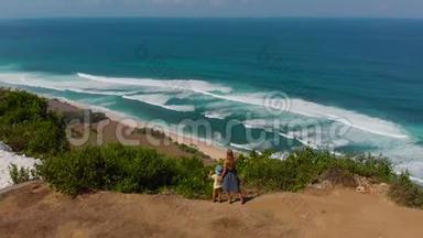 一名年轻女子和她的儿子在巴厘岛的一个偏僻的海滩<strong>上访</strong>问了纽约。 站在岩石上