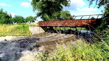一座古老的锈迹斑斑的桥在一条带着暴风雨水的小溪上