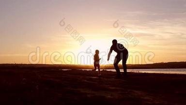 剪影，和爸爸妈妈一起快乐的孩子，日落时分的家人，夏天。 快跑，把孩子举起来，拥抱