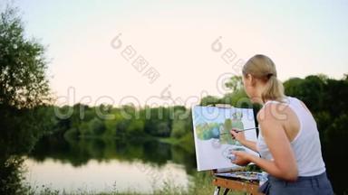 年轻艺术家在公园里用画笔和色彩坐在浪漫的湖泊和城市建筑旁。