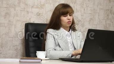 漂亮的女孩坐在<strong>办公室</strong>的椅子上，<strong>用</strong>笔记本<strong>电脑</strong>打字。 年轻的女商人在<strong>电脑</strong>上工作。 女孩