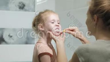 妈妈<strong>轻轻地</strong>刷牙她心爱的女儿的牙齿一个小女孩和她的母亲<strong>轻轻地</strong>清洁牙齿后，吃。