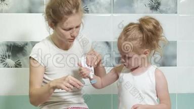 妈妈<strong>轻轻</strong>地刷牙她心爱的女儿的牙齿一个小女孩和她的母亲<strong>轻轻</strong>地清洁牙齿后，吃。