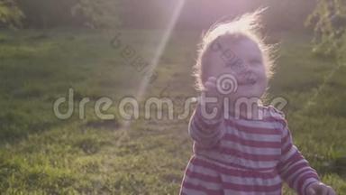 快乐的小女孩走在草地上走向妈妈，带着一颗古老的心在春天的公园里。