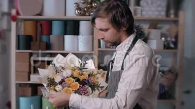 快乐微笑的花店老板在花店做一束。 人，商业，销售和花卉的概念。 玫瑰花束