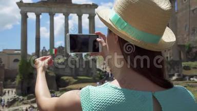 女士靠近论坛罗曼努姆在手机上拍照。 女游客拍照罗马论坛