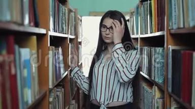 漂亮的小女孩留着长长的黑发在图书馆的书架之间。