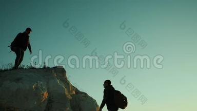 旅行者帮助登山者爬上一座山。 步行旅游徒步旅行冒险登山日落