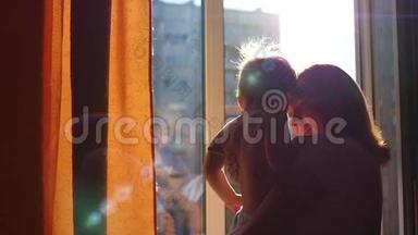 窗前的女孩在阳光下亲吻一个孩子