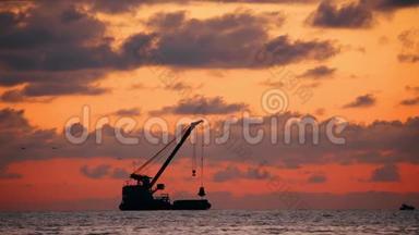 日落时海平线上的日落。 在海景的地平线上渔船的黑暗剪影。 自然日出天空