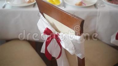 在婚宴或招待会上，白色的椅子和红色的蝴蝶结贴在室内。 结婚装饰品。 大日子。
