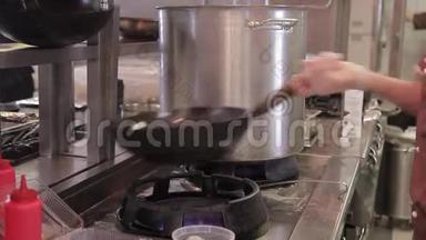 厨师在一个大火上用一个深<strong>油炸锅</strong>拌菜。