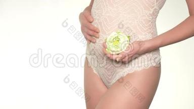 一个孕妇抱着一朵<strong>白莲花</strong>在她肚子旁边的特写镜头