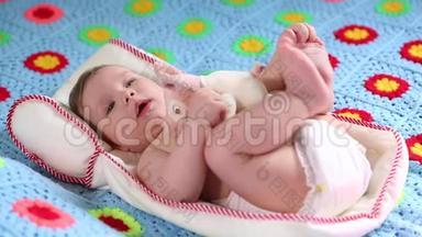 美丽的微笑宝宝：一个漂亮的小宝宝躺在床上，对着相机微笑，轻轻地聚焦着