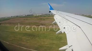 从窗口可以看到一架飞机的机翼，该飞机低空降落在机场