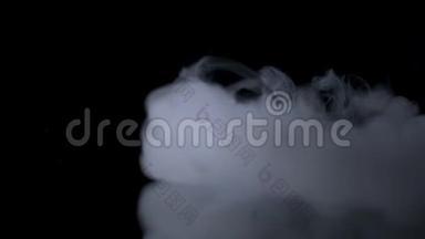 白色的烟雾在黑色的背景下慢慢地飘过空间。 雾效应。 大气烟雾。 雾霾背景