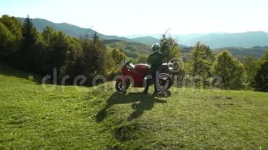 一个骑摩托车的人。 带着摩托车在山上的年轻帅哥。 他站在摩托车旁边