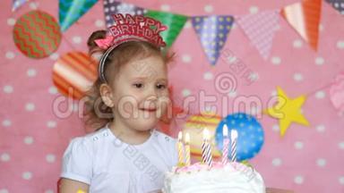 生日快乐。 可爱的孩子<strong>许愿</strong>，在聚会上吹灭蛋糕上的蜡烛。 有趣的小<strong>女孩</strong>。 粉色背景。