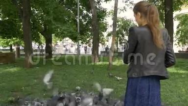 一个悲伤的漂亮女孩在公园里喂鸽子。