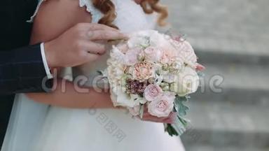 快乐的新娘和新郎。 你的手。 新郎用花束拥抱新娘。 幸福的眼泪。 特写