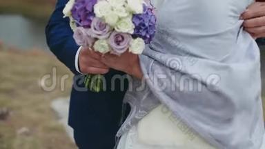 快乐的新娘和新郎。 你的手。 新郎用花束拥抱新娘。 幸福的眼泪。 特写
