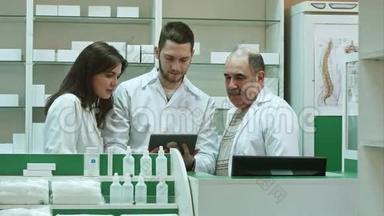 在药房柜台使用平板电脑的三名药剂师
