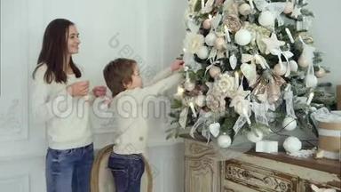 小男孩站在椅子上帮妈妈装饰圣诞树