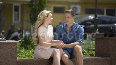 女朋友和男朋友坐在长凳上，手拉手，聊天，谈恋爱