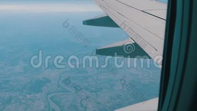 飞机的机翼穿过舷窗。 飞机飞过美丽的空中云层