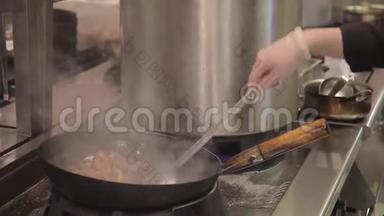 在工业餐厅厨房的灶台上用煎锅搅拌UDON和蔬菜