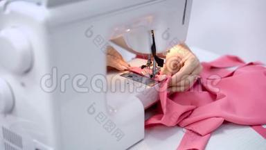在裁缝室里用缝纫机工作的女工的手。 粉布缝合工艺