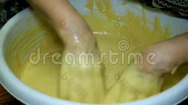 女面包师用手在厨房的一个大碗里大力揉面团。