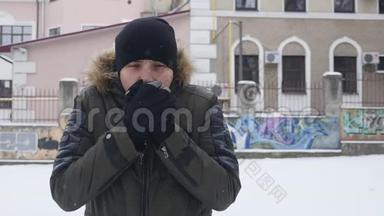 戴着黑帽子的年轻人在寒冷的冬天天气里<strong>暖手</strong>的肖像。 快关门。 户外活动